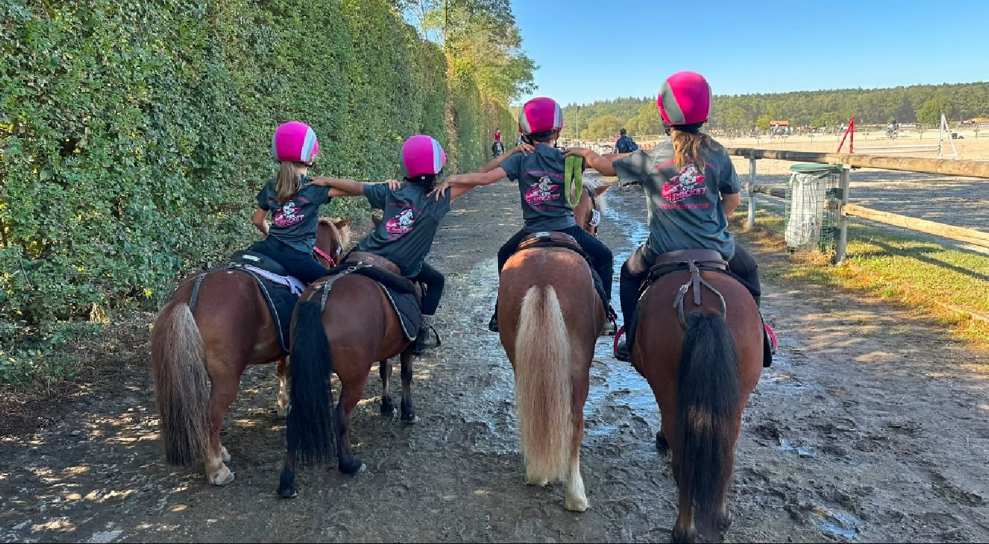 Quatre cavaliers vus de dos portant les T-shirts du poney-club lors de l’événement